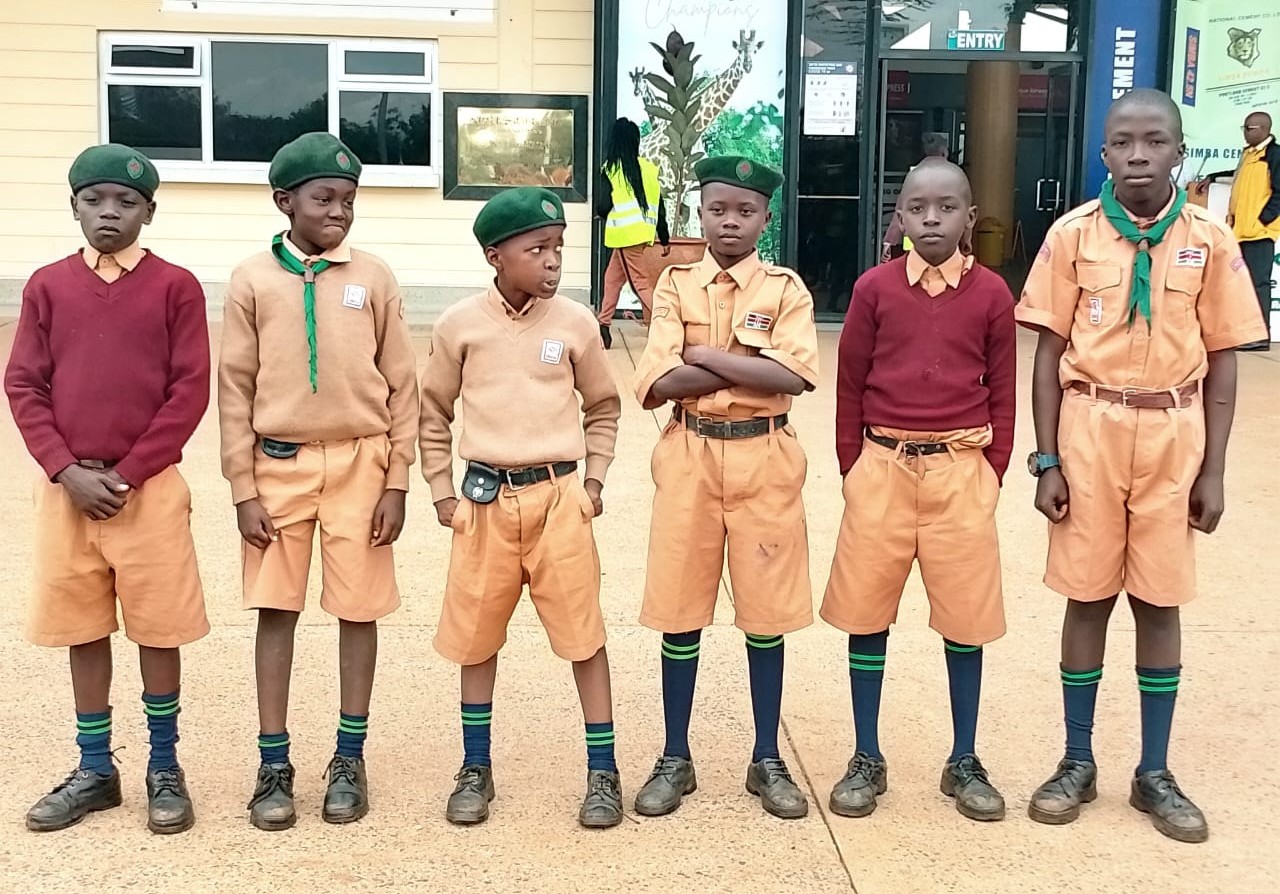 A groups of Scouts in uniform stand looking at the camera.